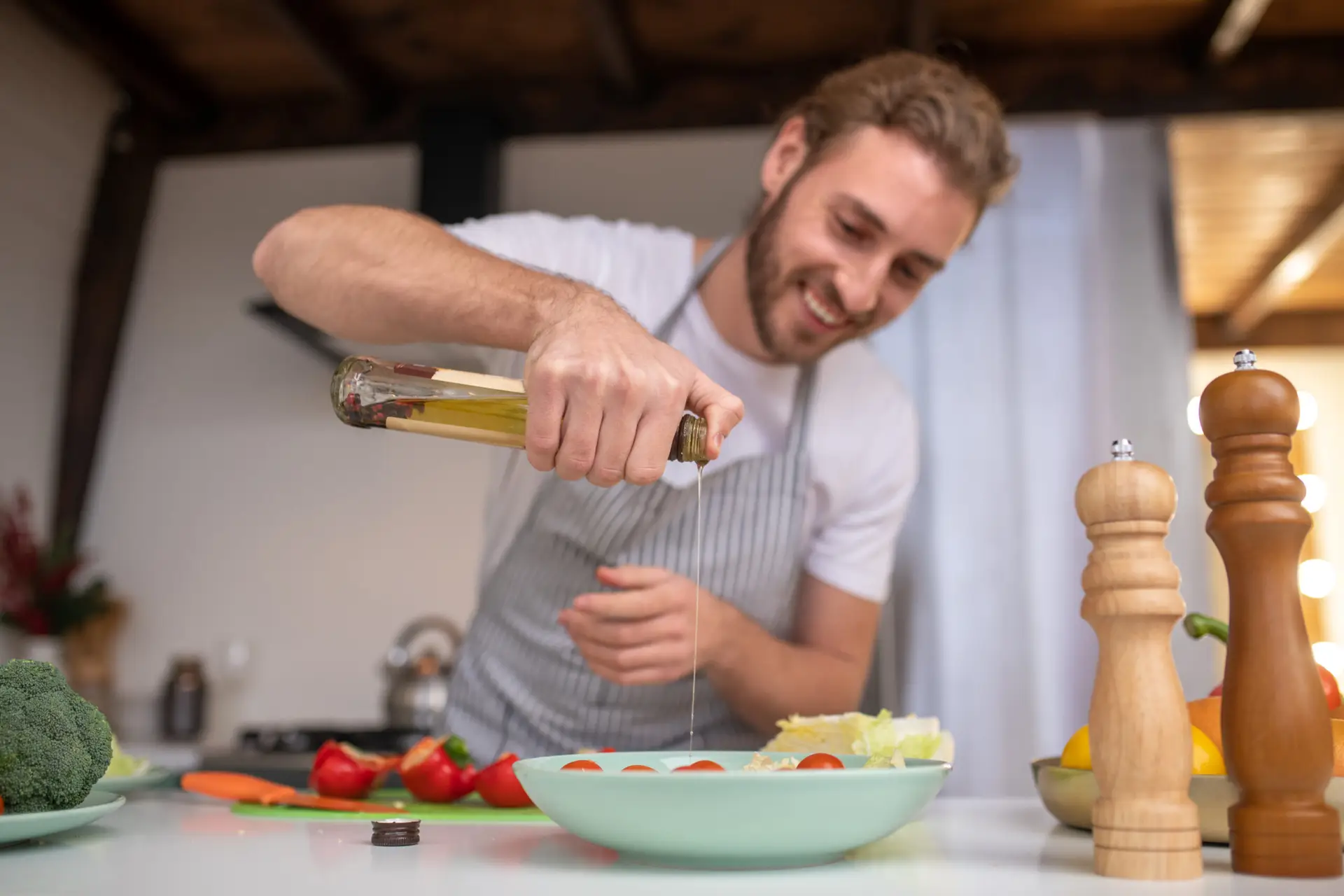 Filling a salad. A concentrated cook putting some oil into a salad